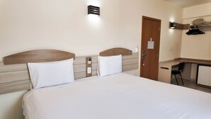Habitació d'hotel amb un llit, una taula de treball i una porta.