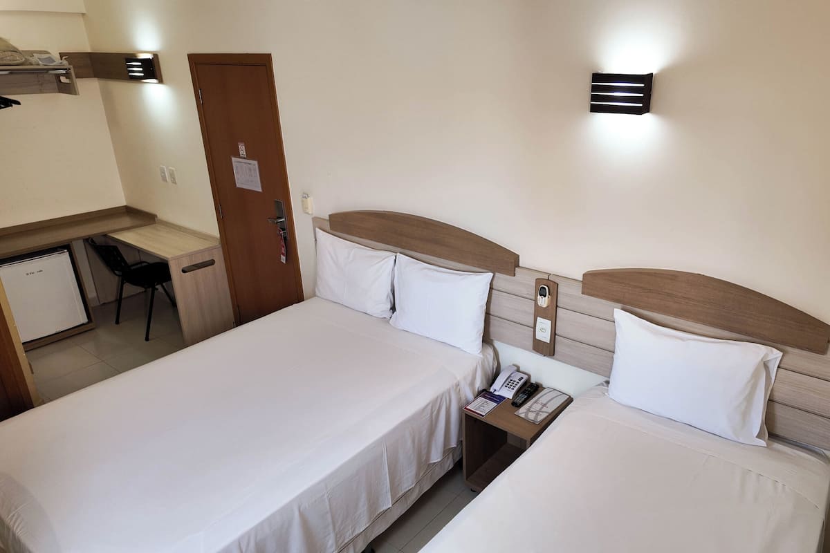 Habitación de hotel con dos camas, un escritorio, una silla, un refrigerador y un teléfono instalado en la pared.