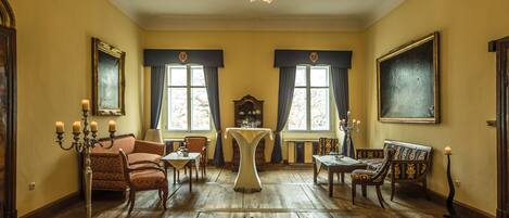 A room with wooden flooring, a chandelier, a table, and several chairs.