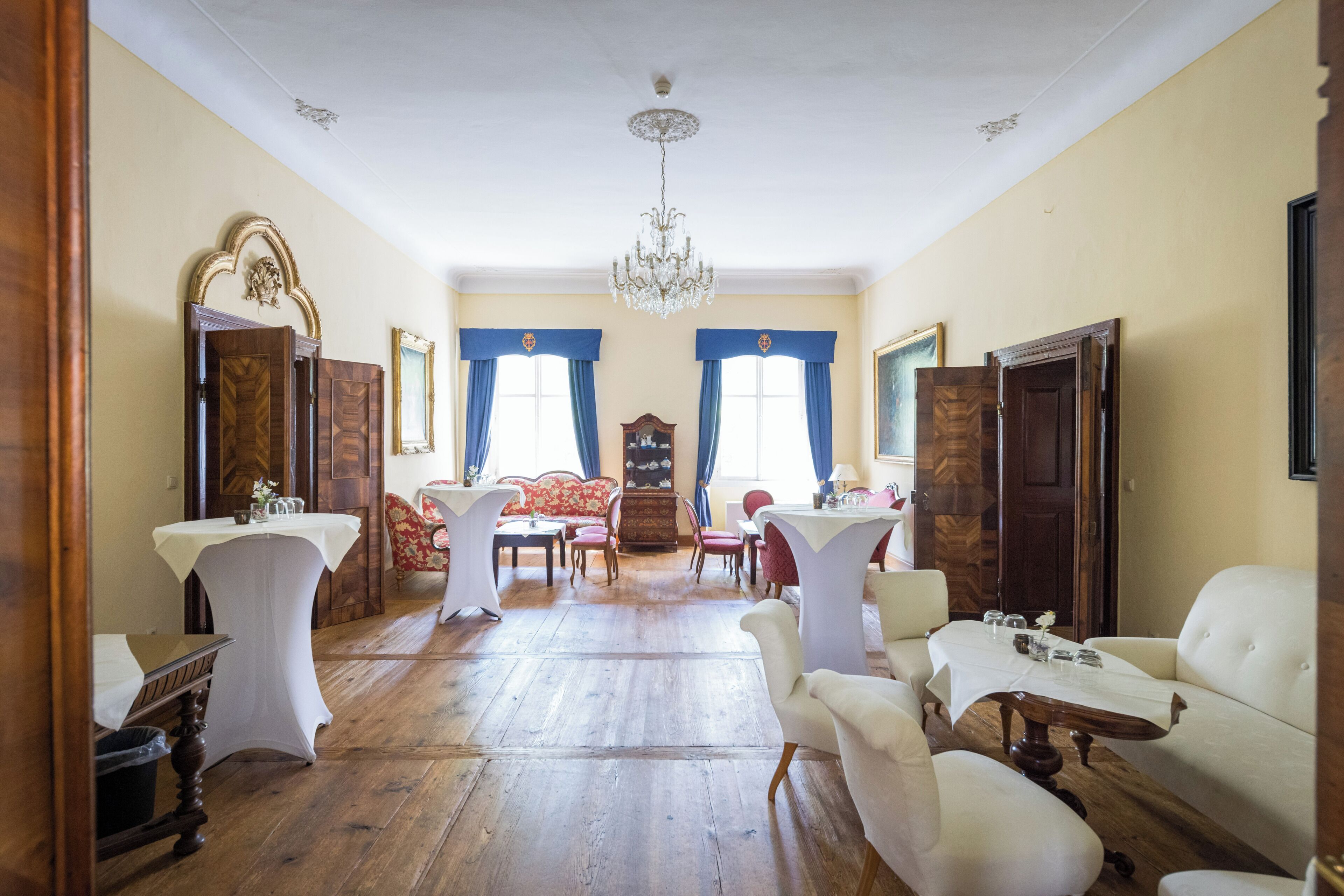 A room with wooden flooring, white furniture, and a chandelier.