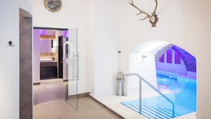Interior moderno de un hotel con una puerta de vidrio que da a un baño, una escalera con vista a una piscina y un par de astas de venado montadas en la pared.