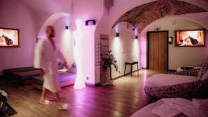 Una sala de spa con un banco de madera, una camilla de masaje y una cama con cabecera estampada.
