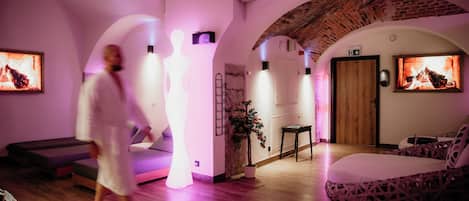 Una sala de spa con un banco de madera, una camilla de masaje y una cama con cabecera estampada.