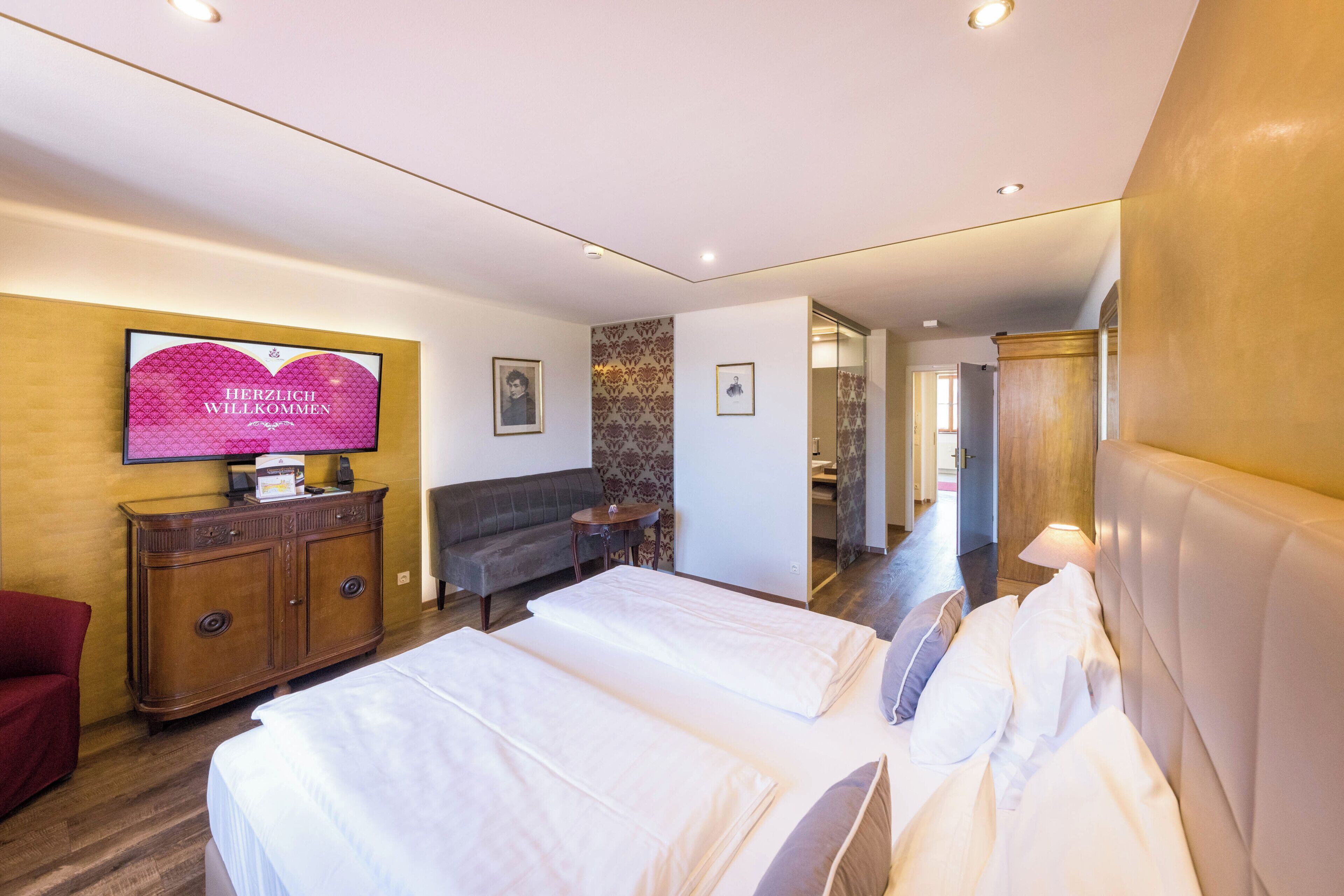 Una habitación de hotel con cama, sofá, televisor y un armario de madera.