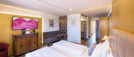 Una habitación de hotel con cama, sofá, televisor y un armario de madera.