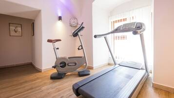 Un gimnasio en casa con una cinta de correr, una elíptica y una bicicleta estática.
