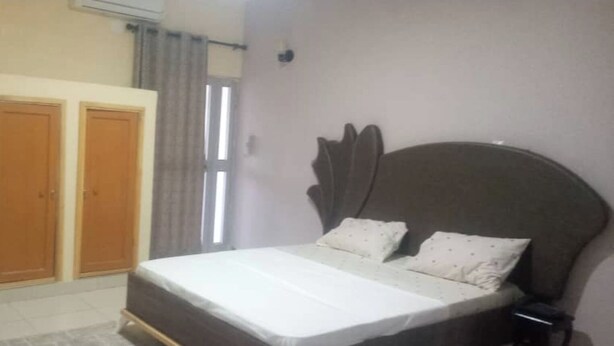 Una camera da letto con un letto, due armadi, una finestra con tende e un condizionatore d'aria a parete.