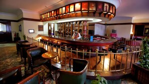 Eine Bar mit einer gebogenen Theke, verschiedenen Sitzmöglichkeiten und einer dekorativen Decke.