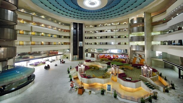 Ein mehrgeschossiges Hotelatrium mit einem zentralen Innenhof, mehreren Balkonen und einem markanten Deckenstil.