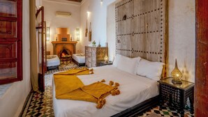 Une chambre de style traditionnel, dotée d’un grand lit, d’une cheminée et d’un panneau décoratif mural.