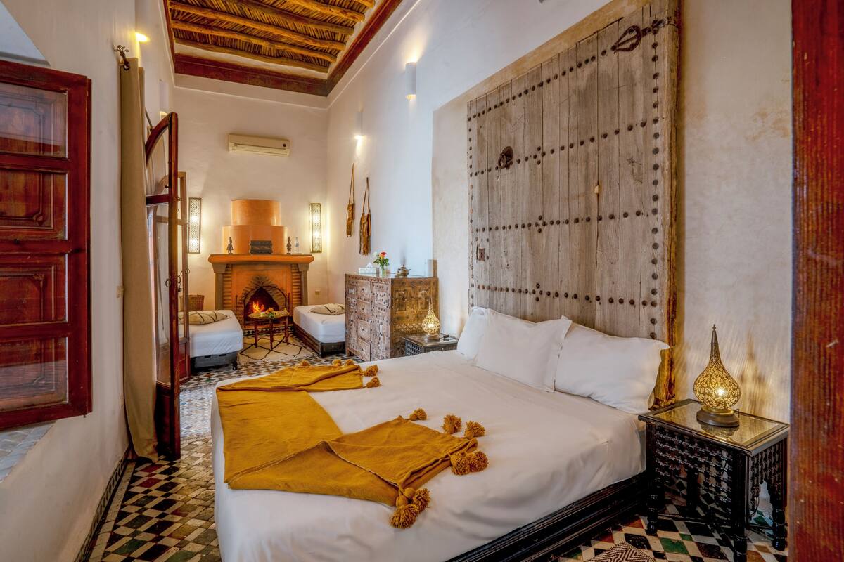 A traditional room with a large bed, a fireplace, and a decorative wall panel.