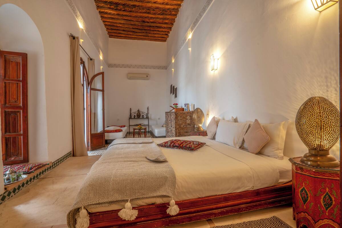 A spacious bedroom with a large bed, a wooden ceiling, and a decorative lamp.