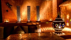 Une pièce avec un sol carrelé, une table décorée de bougies et une lampe d’appoint.