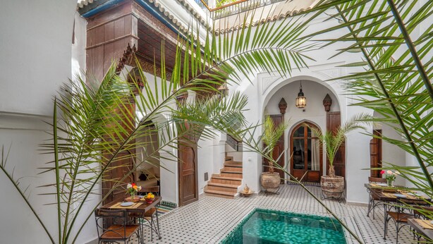 Une cour avec une piscine, des palmiers et un escalier menant à un niveau supérieur.