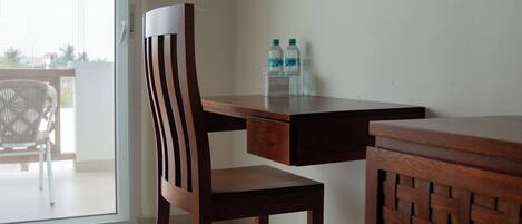 A wooden chair and table with two water bottles on a balcony.