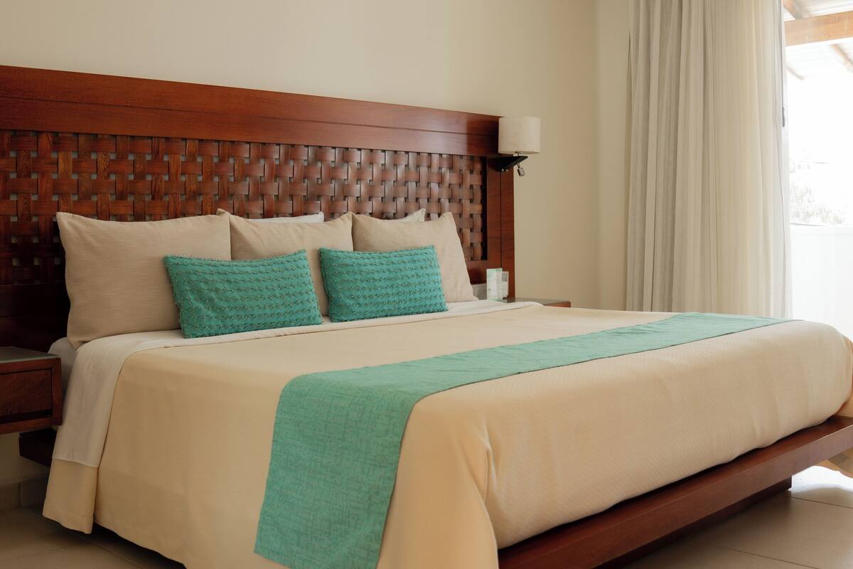 A bed with a wooden headboard, two pillows, a bedside table, and a lamp.