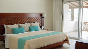 A hotel room with a large bed, wooden headboard, and a view of the outside balcony. - Blater Hotel (Santa Maria Colotepec)