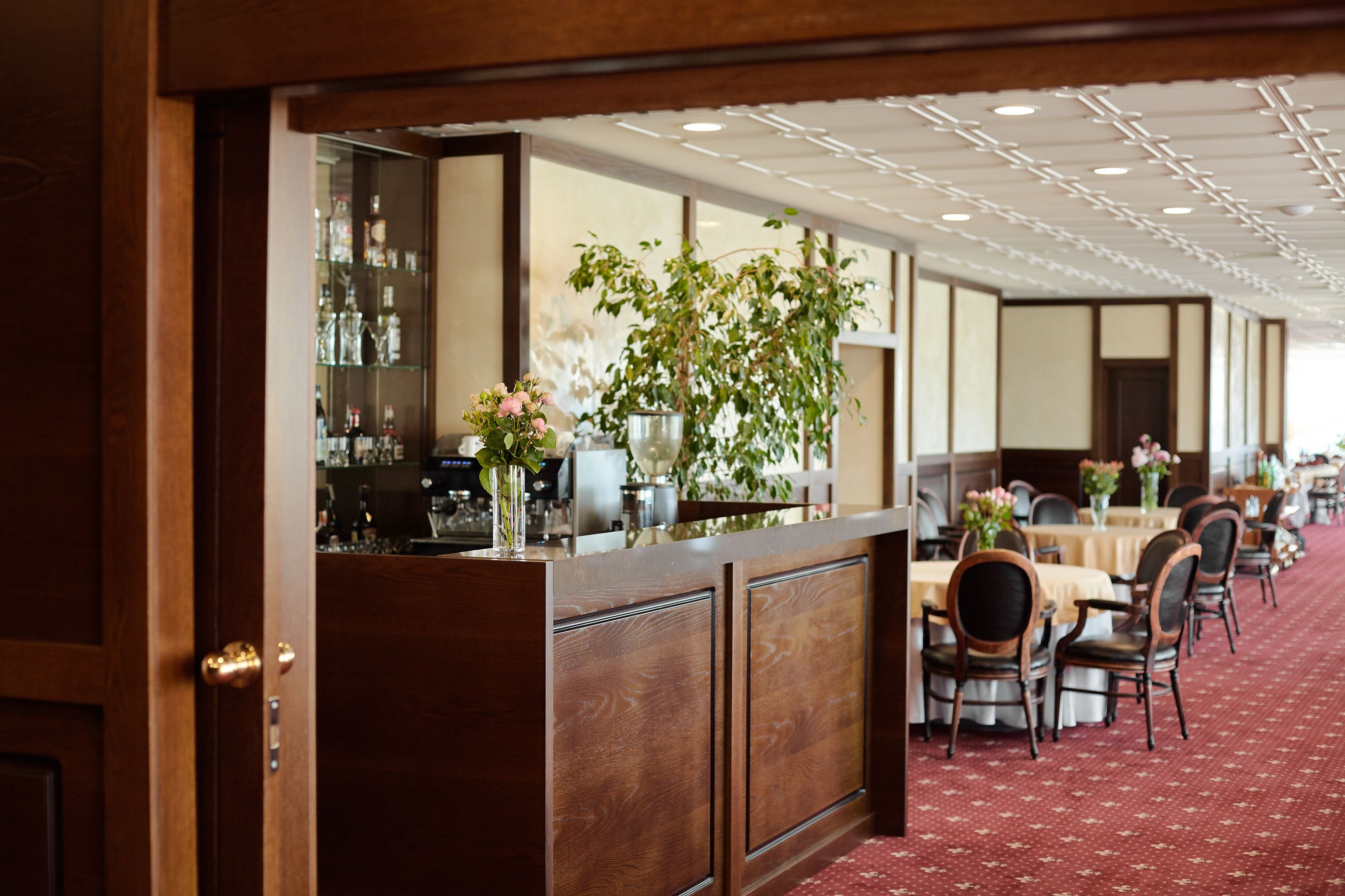 A hotel lobby with a reception desk, seating area, and a large plant.