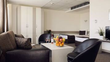 Una habitación de hotel moderna con comedor, sofá, mesa de centro y televisión.