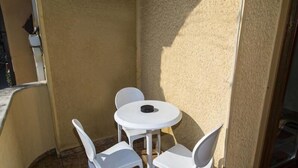 A small outdoor patio with a round table and four white chairs. - Apart Hotel Kalonis Skopje (Skopje)