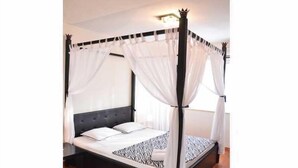 A four-poster canopy bed with white drapes, a tufted headboard, and a zebra-patterned bedspread. - Apart Hotel Kalonis Skopje (Skopje)