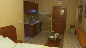 A compact living space with a kitchenette, a sofa, and a small table with tea set. - Hotel Portal (Skopje)