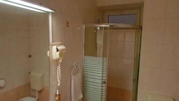 A bathroom with a sink, toilet, and a glass-enclosed shower stall.