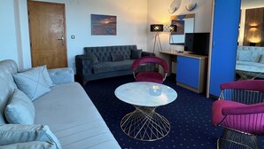 A modern hotel room with a sofa, a dining table, a TV, and a desk. - Saint George Nessebar (Nessebar)