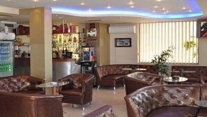 A bar area with leather sofas and a bar counter stocked with bottles. - Saint George Nessebar (Nessebar)