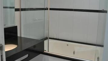 Un baño moderno con cabina de ducha de vidrio, una bañera blanca y un mostrador negro.