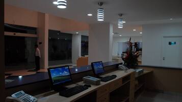 Una mesa de recepción con computadoras, un teléfono y una planta.