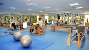 Un gimnasio con equipo de ejercicio, espejos y colchonetas azules.