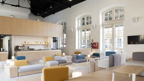 Un'area lounge moderna con divani, tavolini e un angolo bar con bottiglie e bicchieri.
