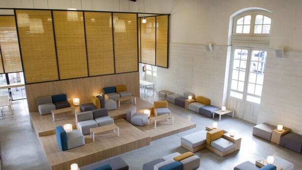 Un'area lounge moderna con diverse opzioni di seduta, tra cui divani e poltrone, disposte su una piattaforma in legno.