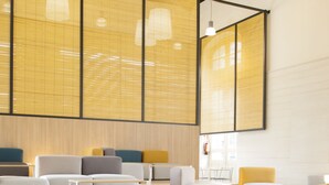 Un interno moderno con zone relax, tavoli e ampie finestre dotate di tende.