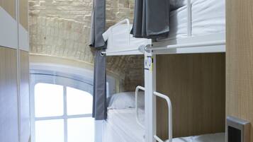 A bunk bed room with a stone wall and a window.