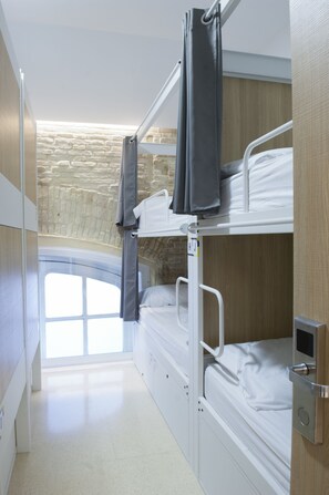 A bunk bed room with a stone wall and a window. - Up Station Hostel (Valencia)