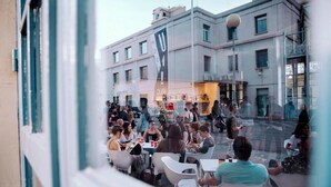 Un gruppo di persone sta cenando all'aperto in un ristorante, con un edificio sullo sfondo.