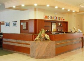 A reception desk with a marble base, framed pictures on the wall, and a floral arrangement.