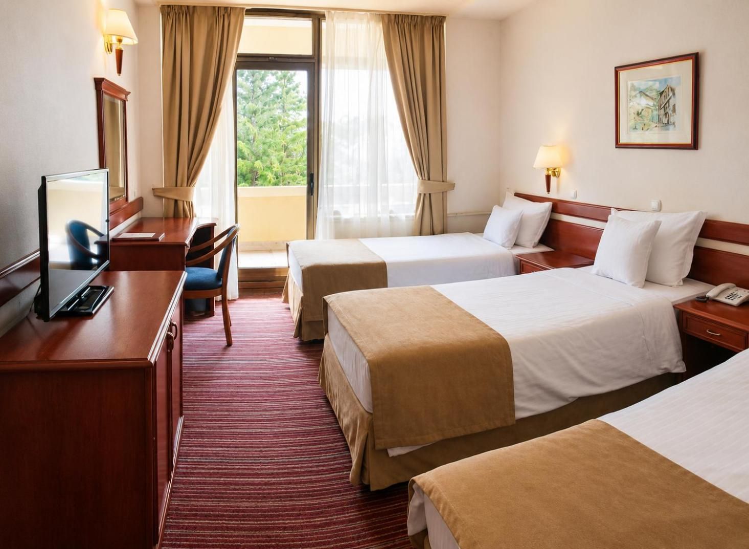 Habitación de hotel con dos camas, un escritorio con computadora, una silla y una ventana con cortinas.