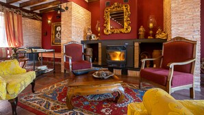 A cozy living room with a fireplace, red walls, and wooden furniture. - Posada De Eufrasio (Lerma)