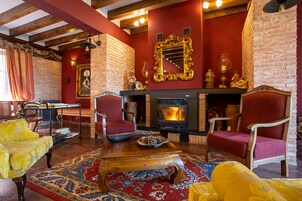 A cozy living room with a fireplace, red walls, and wooden furniture.