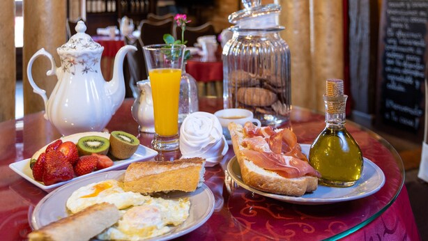 A breakfast table with a teapot, juice, toast, eggs, and a bottle of oil. - Posada De Eufrasio (Lerma)