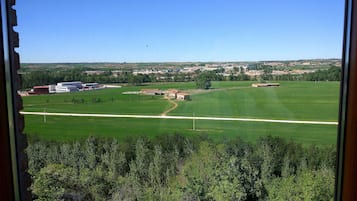 A view of a green field with buildings in the distance.