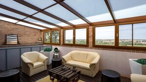 A covered outdoor seating area with two beige sofas, a wooden coffee table, and a small round table. - Posada De Eufrasio (Lerma)