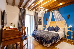 Quarto com cama de madeira, uma cadeira de madeira, mesa de cabeceira com abajur e lustre.