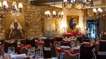 Un restaurant aux murs de pierre, aux lustres étincelants et aux nappes rouges.