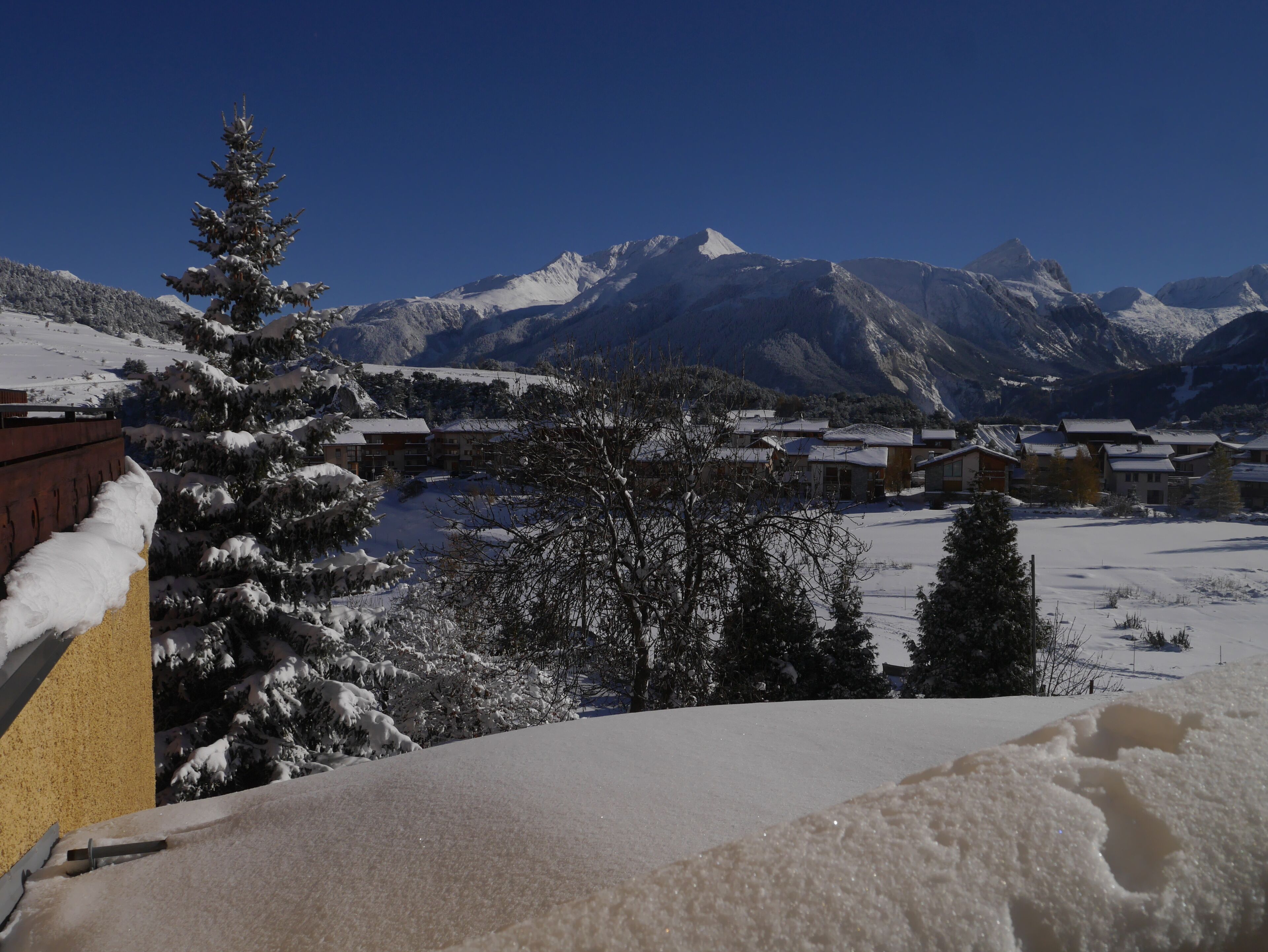 Un paysage de montagne enneigé, avec un village et des bâtiments au premier plan.