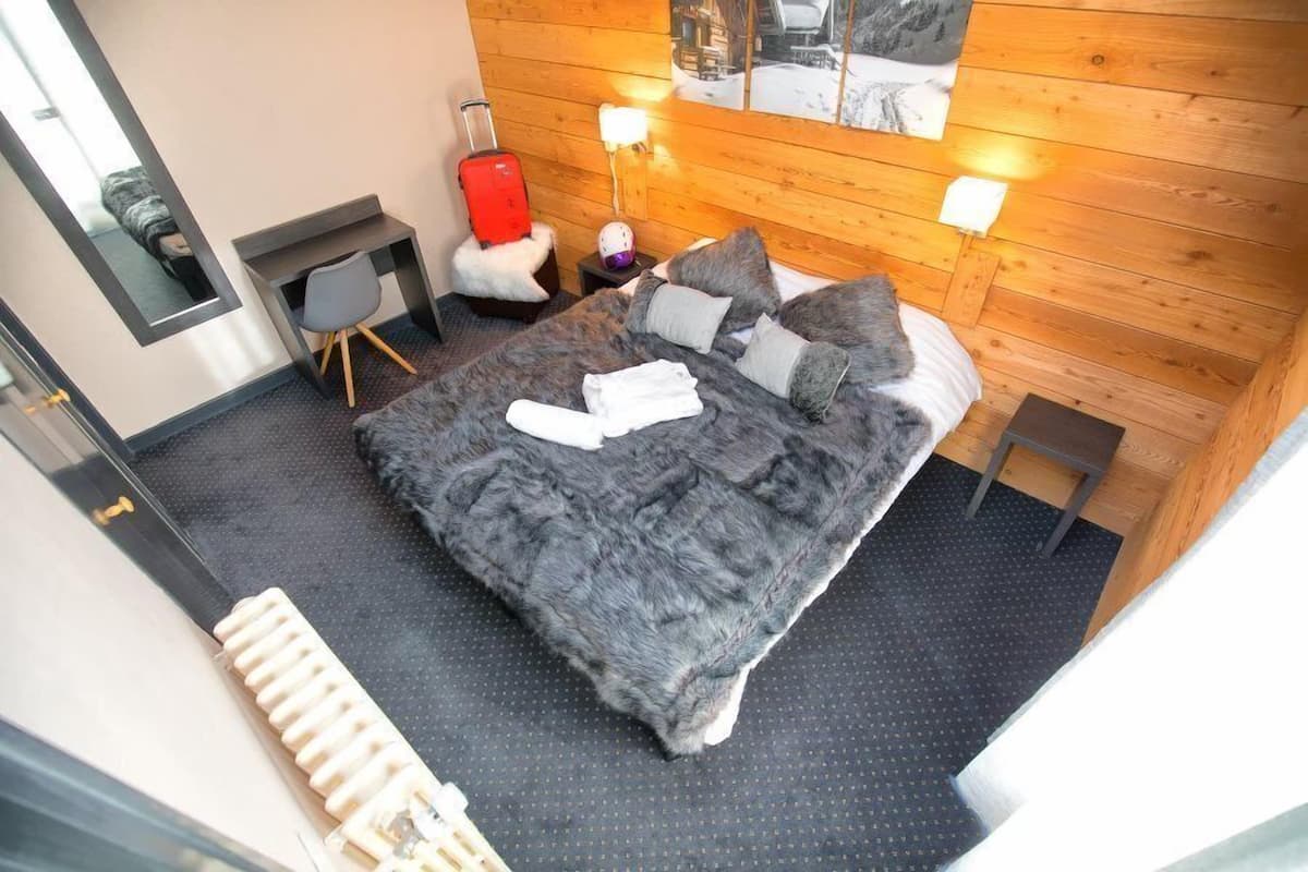 Una habitación de hotel moderna con una cama grande, un escritorio, una silla y una maleta.