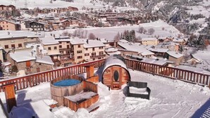 Un pueblo cubierto de nieve con edificios de madera, una bañera de hidromasaje de madera y una valla de madera.